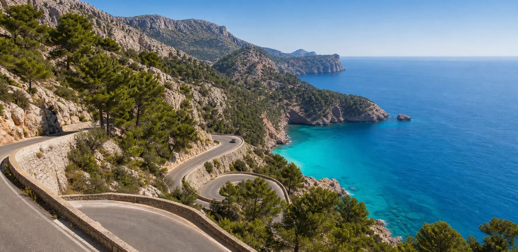 A mountain road winding above a turquoise cove in Mallorca